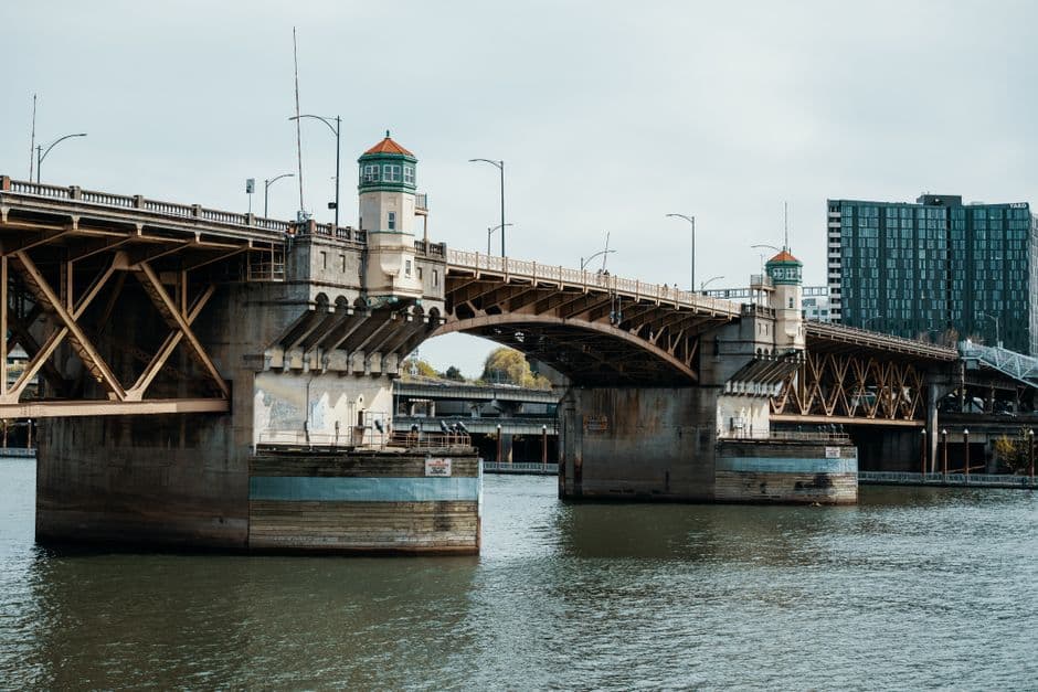 The Burnside Bridge over the Willamette River in Portland, Oregon, seen from the water, with two small towers on its concrete piers