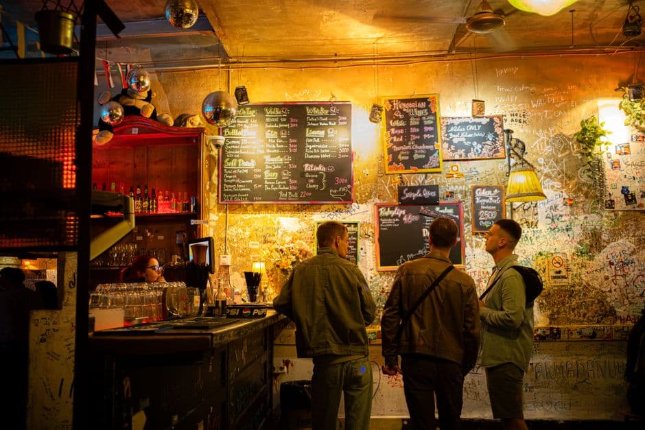 The cluttered interior of a Budapest ruin bar in District VII, with mismatched furniture and hanging lights in a courtyard of a former tenement