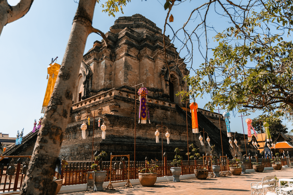 The truncated laterite chedi of Wat Chedi Luang in the Chiang Mai old city, hung with vertical Lanna tung banners in orange, purple and yellow