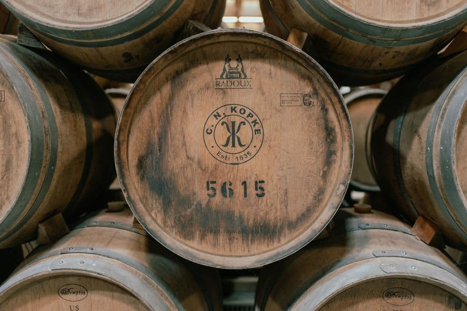 Stacked oak port casks in a cellar, the front one stenciled C. N. Kopke, Estd. 1638, and numbered 5615
