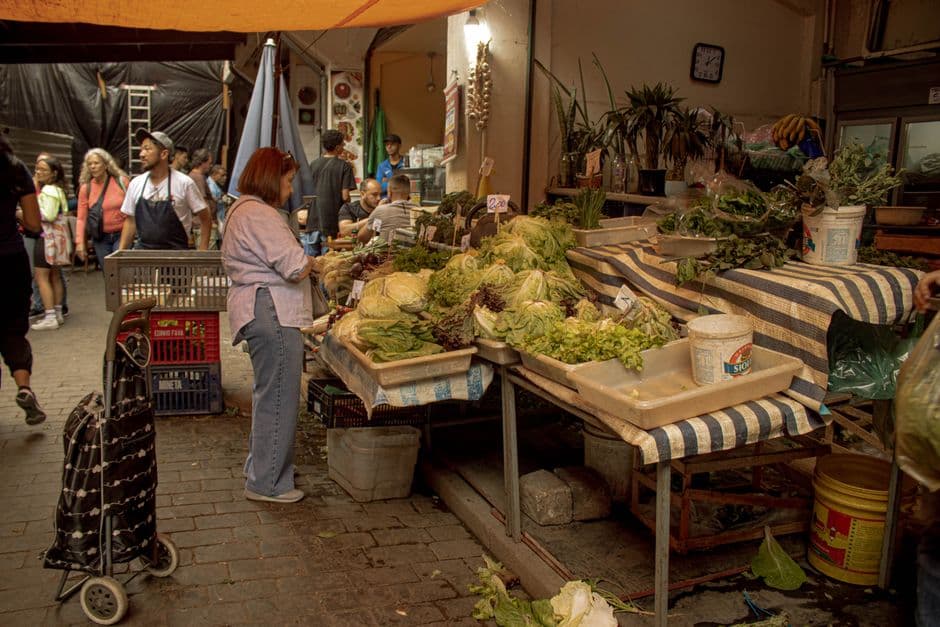 A greengrocer's stall stacked with lettuces and leafy herbs at a covered market