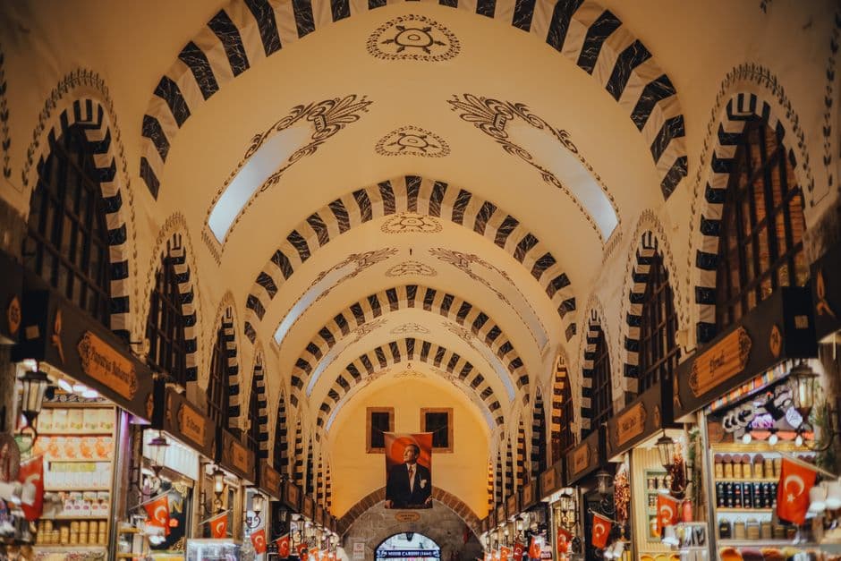 The painted vaulted arcade of the Spice Bazaar in Istanbul, lined with shops and hung with Turkish flags