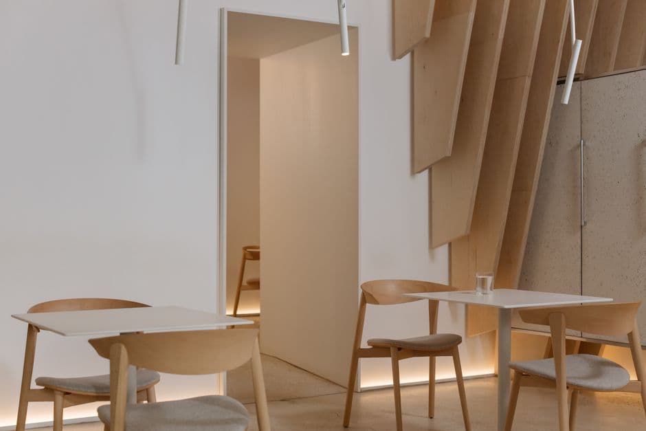 A pale wood and white Scandinavian dining room with small tables set for two