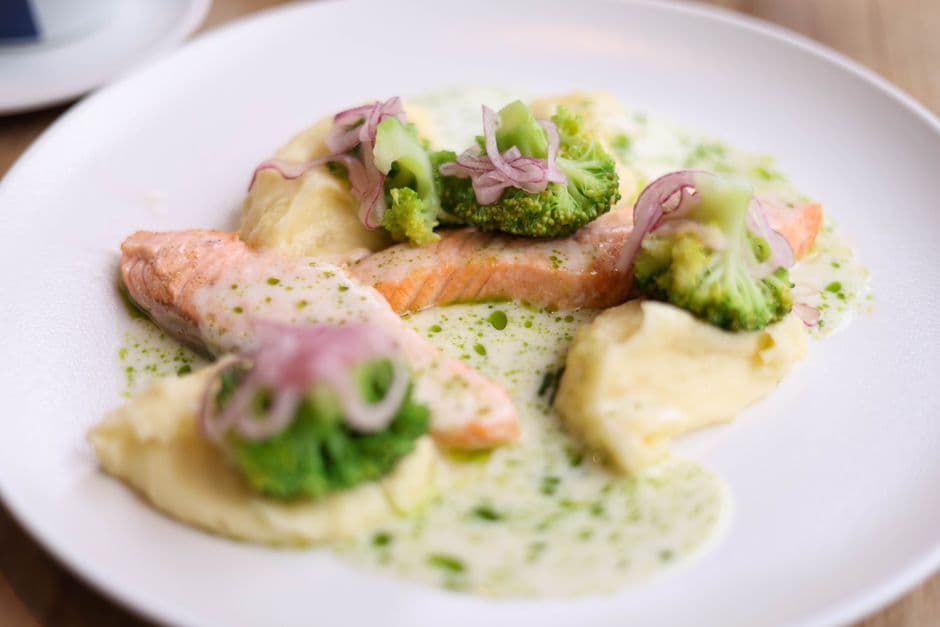 A plate of salmon with mashed potato, cream sauce, greens and pickled red onion, the shape of a Swedish weekday lunch