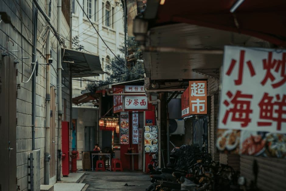 A crowded Asian street food alley at night, dense with unlisted stalls