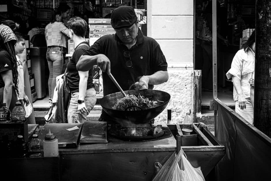 A street food vendor cooking over a wok at a stall, the kind of business that street food rankings struggle to count