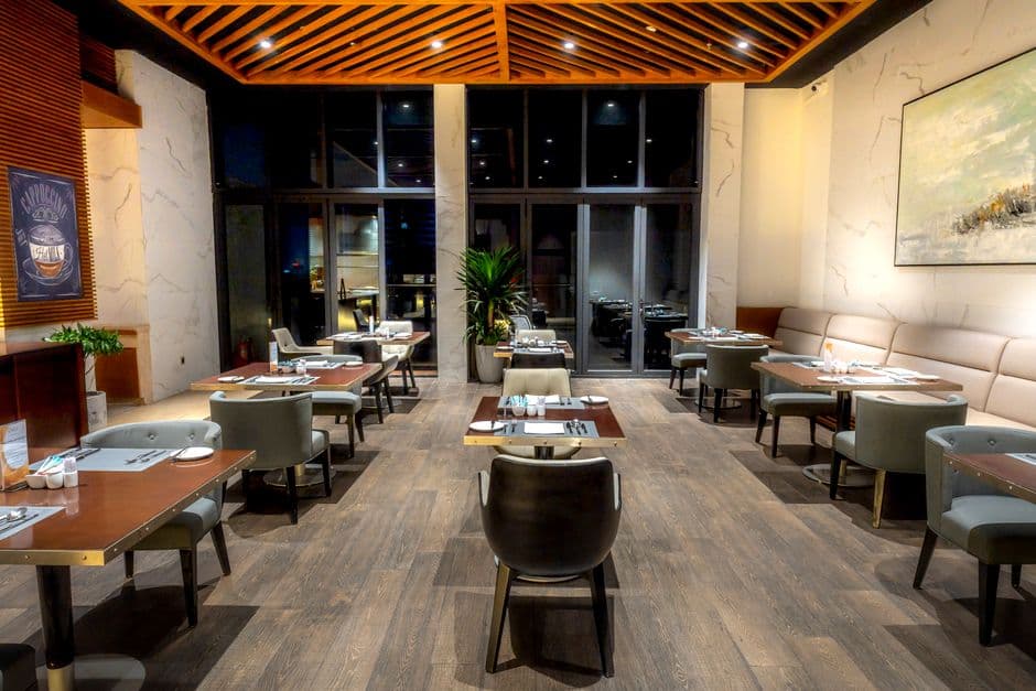 An empty restaurant dining room with tables laid and no diners, seen in the evening