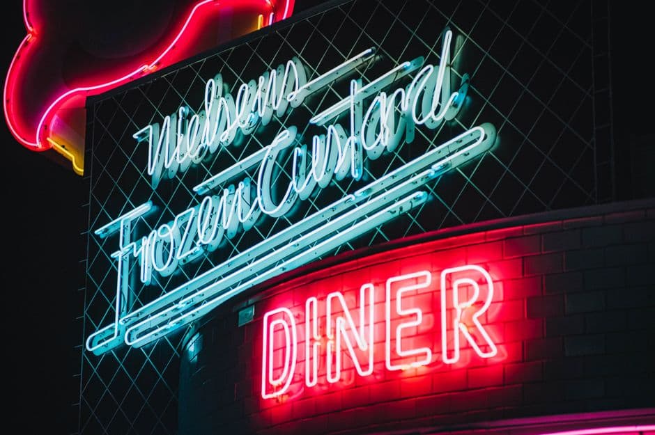 Neon signs for Nielsen's Frozen Custard and a diner glowing in red and blue against a dark night sky