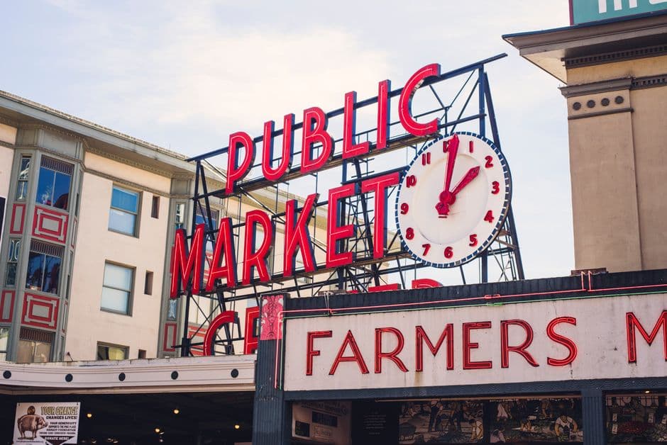 The red neon Public Market Center sign and clock above the Pike Place Market farmers market entrance in Seattle