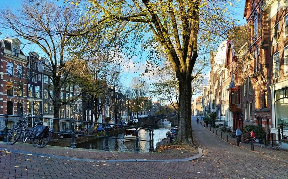 A canal in Amsterdam lined with narrow brick houses and bicycles parked along the railing