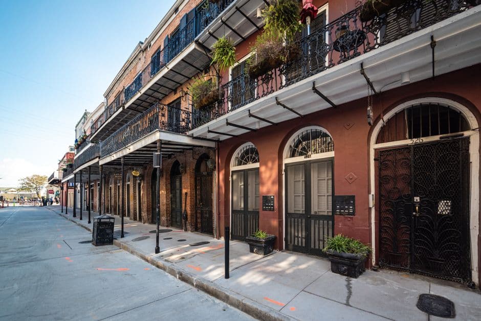 A New Orleans street of nineteenth century townhouses with cast iron balconies and shuttered windows, the architecture of the older neighborhoods where the city's MICHELIN listed restaurants are