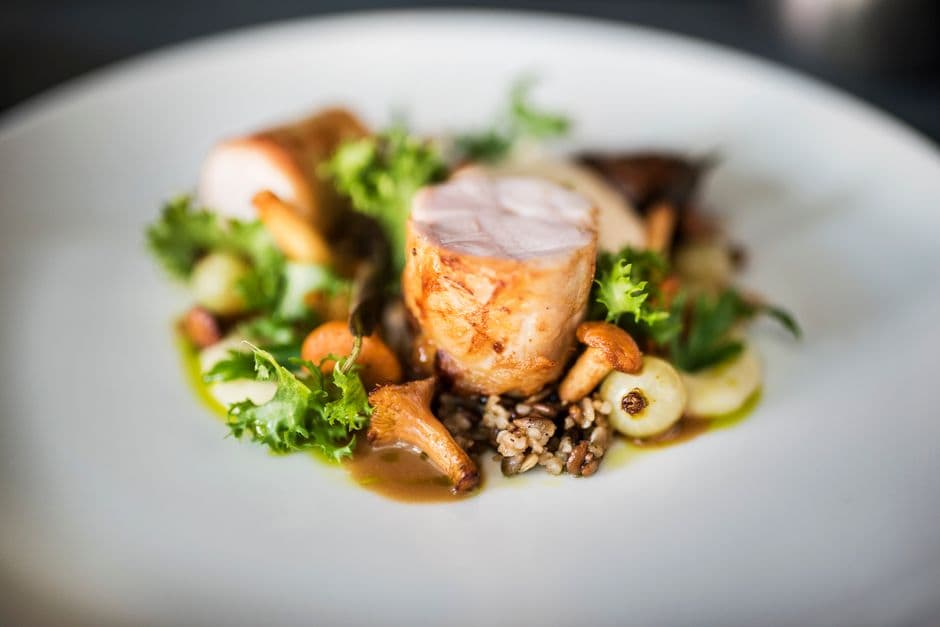 A fine dining plate of roasted meat with chanterelle mushrooms, glazed onions, wild rice and a dark jus