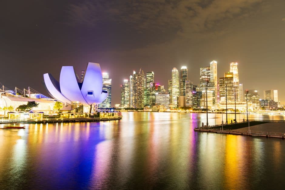 Marina Bay in Singapore at night, with the lotus-shaped ArtScience Museum lit in purple on the left and the lit towers of the financial district reflected in the water