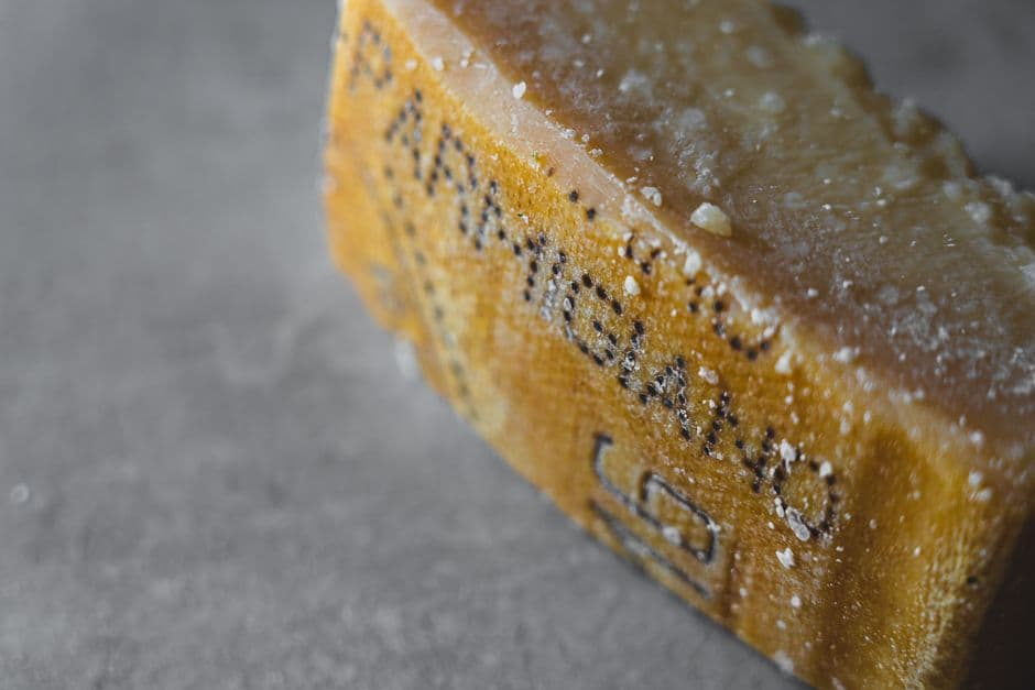 A close view of a wedge of Parmigiano Reggiano with the stenciled dots of the name pressed into its rind