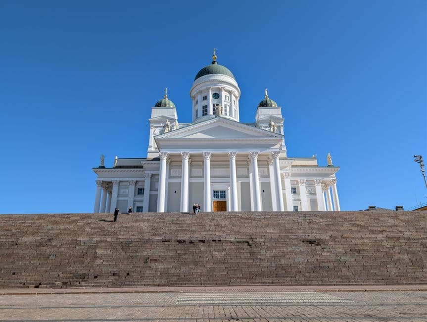 Helsinki Cathedral in white neoclassical stone with its green dome, seen from the foot of the Senate Square steps