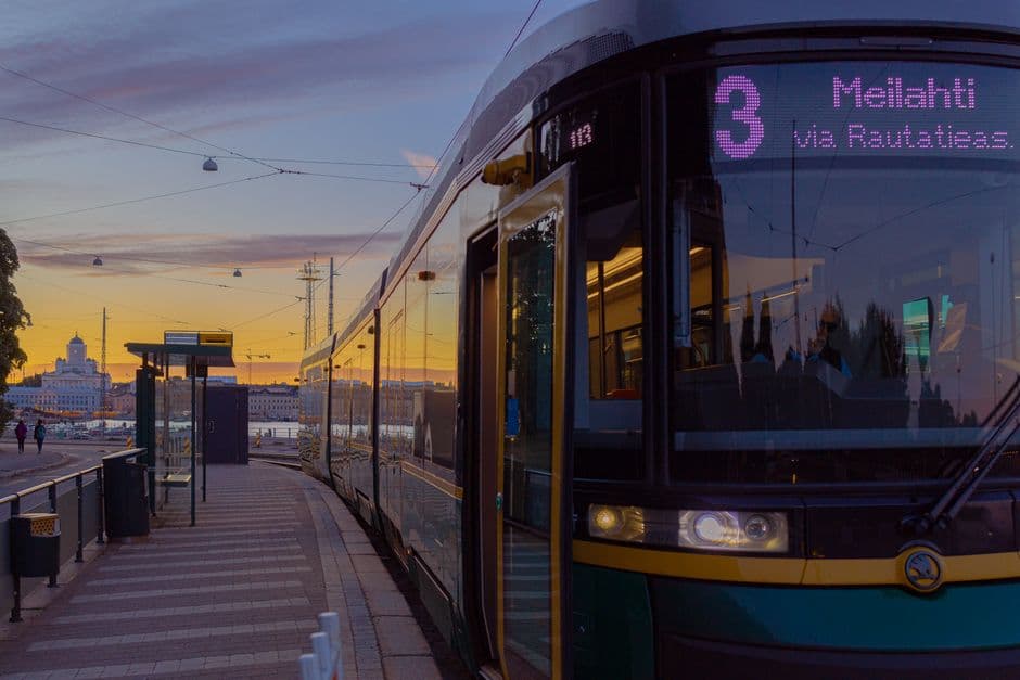 A Helsinki tram on route 3 to Meilahti at sunset, its destination board lit, with the white dome of Helsinki Cathedral on the skyline behind