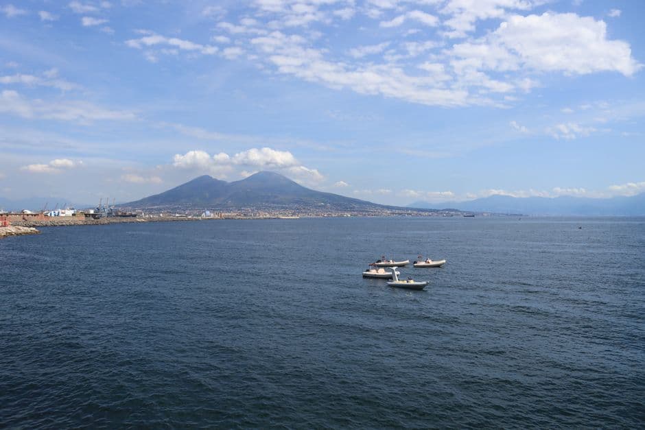 Aerial view of the Bay of Naples with sailing boats on the water and Mount Vesuvius rising behind the coastline
