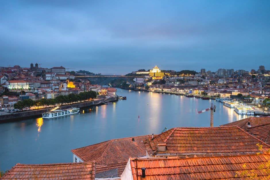 The Douro at dusk seen from Porto, with the upper deck of the Ponte Dom Luis I crossing to Vila Nova de Gaia and the Serra do Pilar monastery lit on the far bank