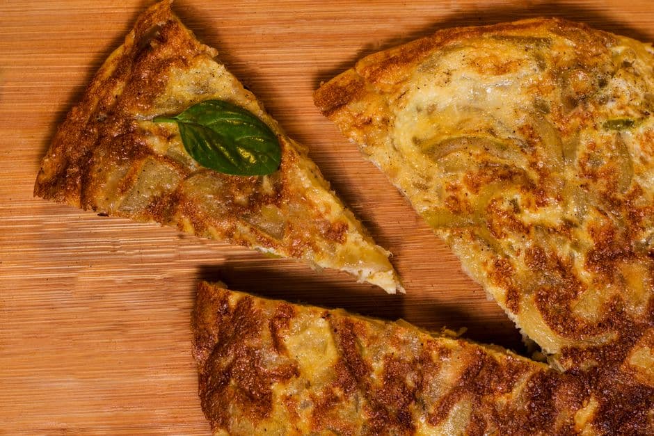 Three thick slices of Spanish potato tortilla with browned edges on a wooden board