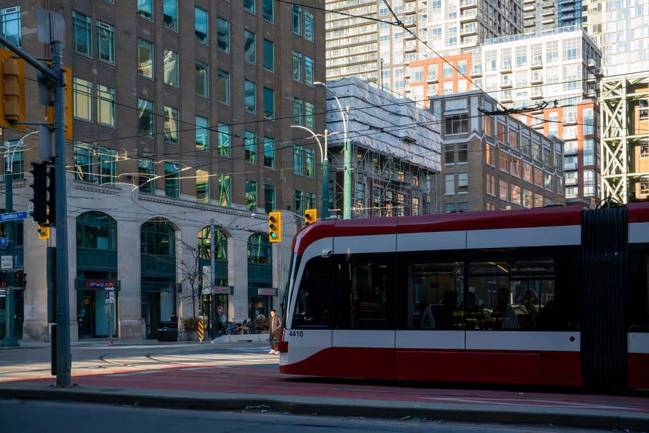 A red and white TTC streetcar crossing an intersection in downtown Toronto, with a Spadina Avenue street sign on the corner