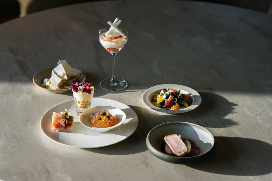 Several small plated tasting-menu courses arranged on a stone table in daylight
