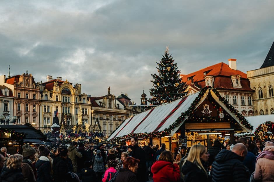 Wooden market stalls and a decorated Christmas tree filling Old Town Square in Prague, with the Church of Our Lady before Týn behind